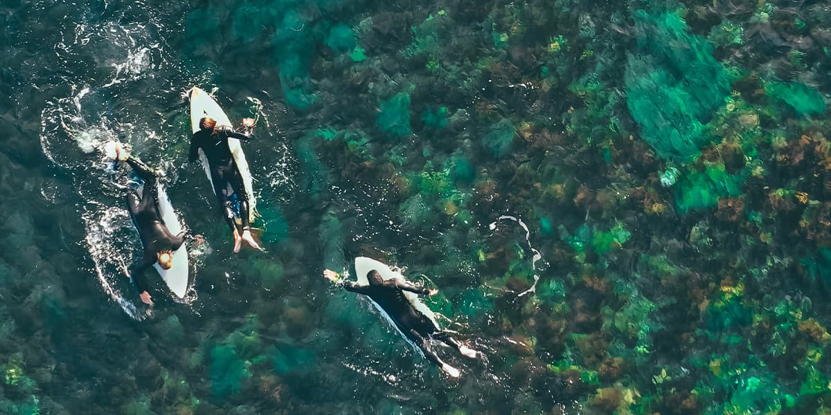 Three surfers paddling out