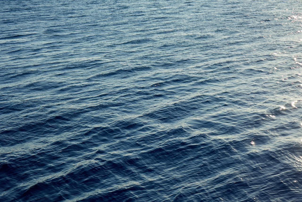 Photo of sea water with the sun light reflected on its small waves