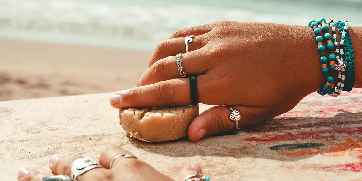 Surfer rubbing wax on surfboard