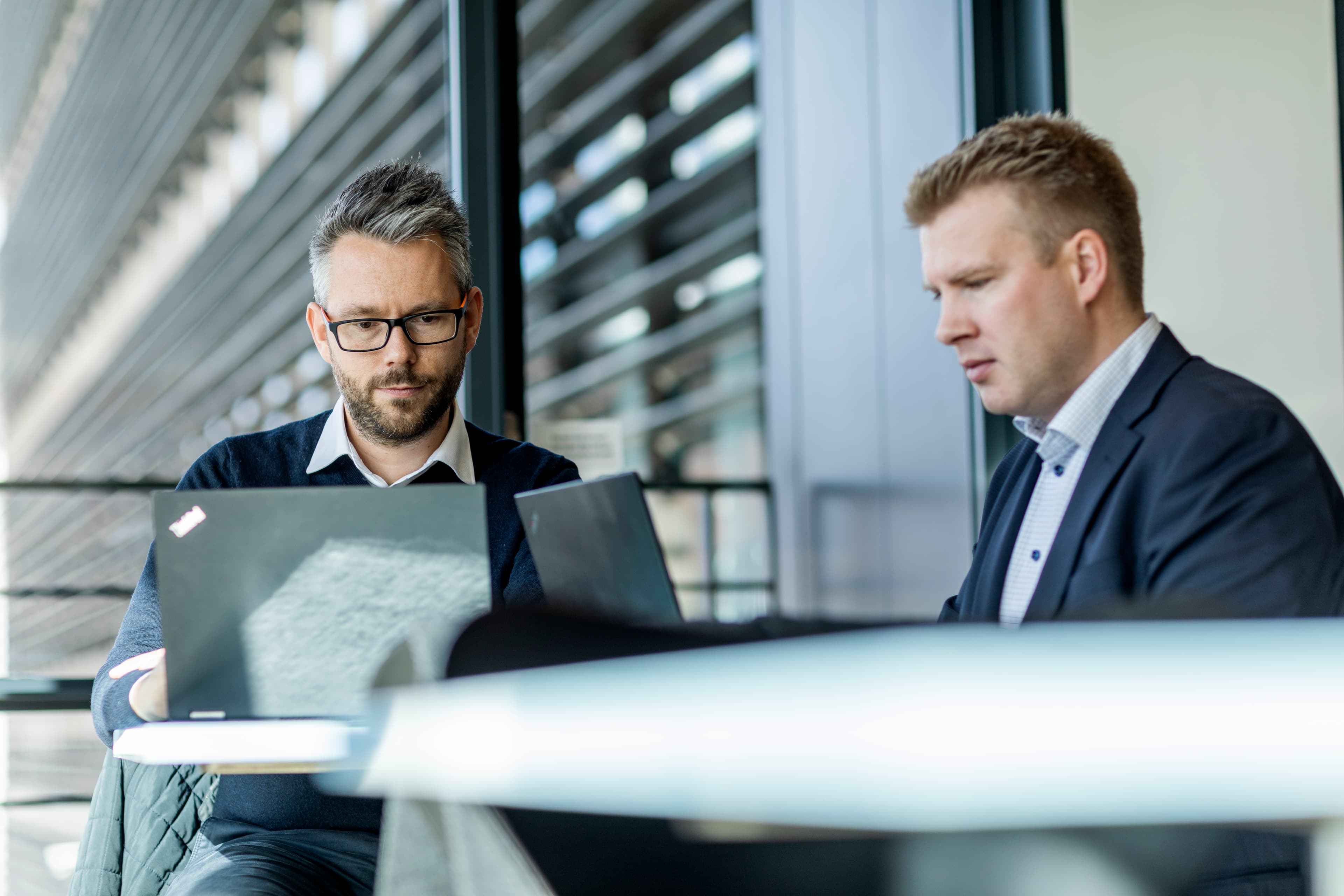 Photo of two male DFDS colleagues at the headquarters office in Copenhagen on their laptops