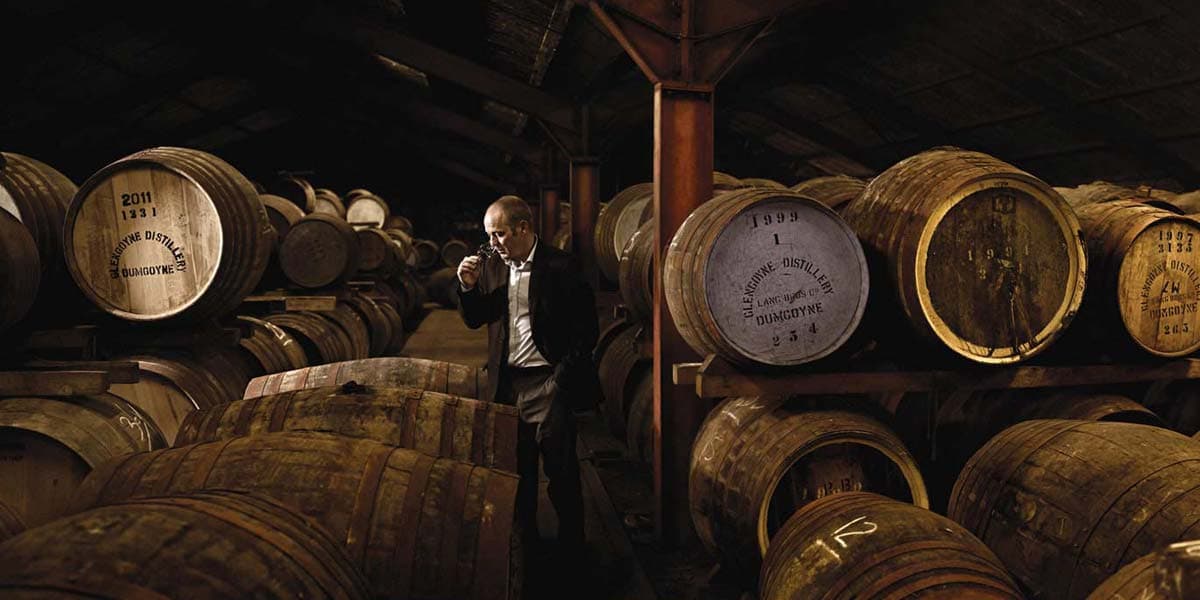 Man standing amongst whisky barrels