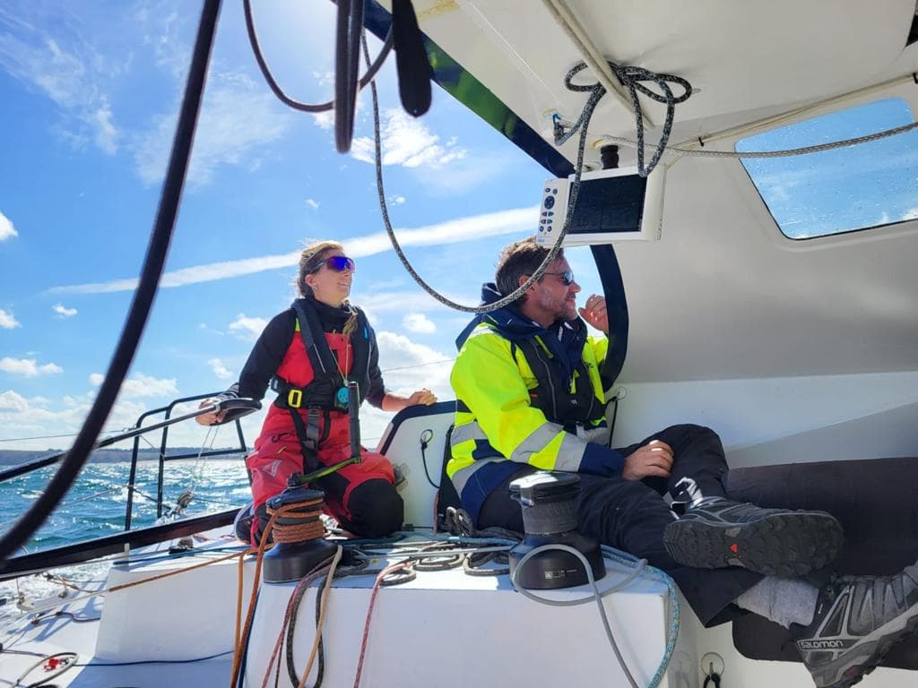 A ship sailing on the sea, with woman & man in the sailing outfit