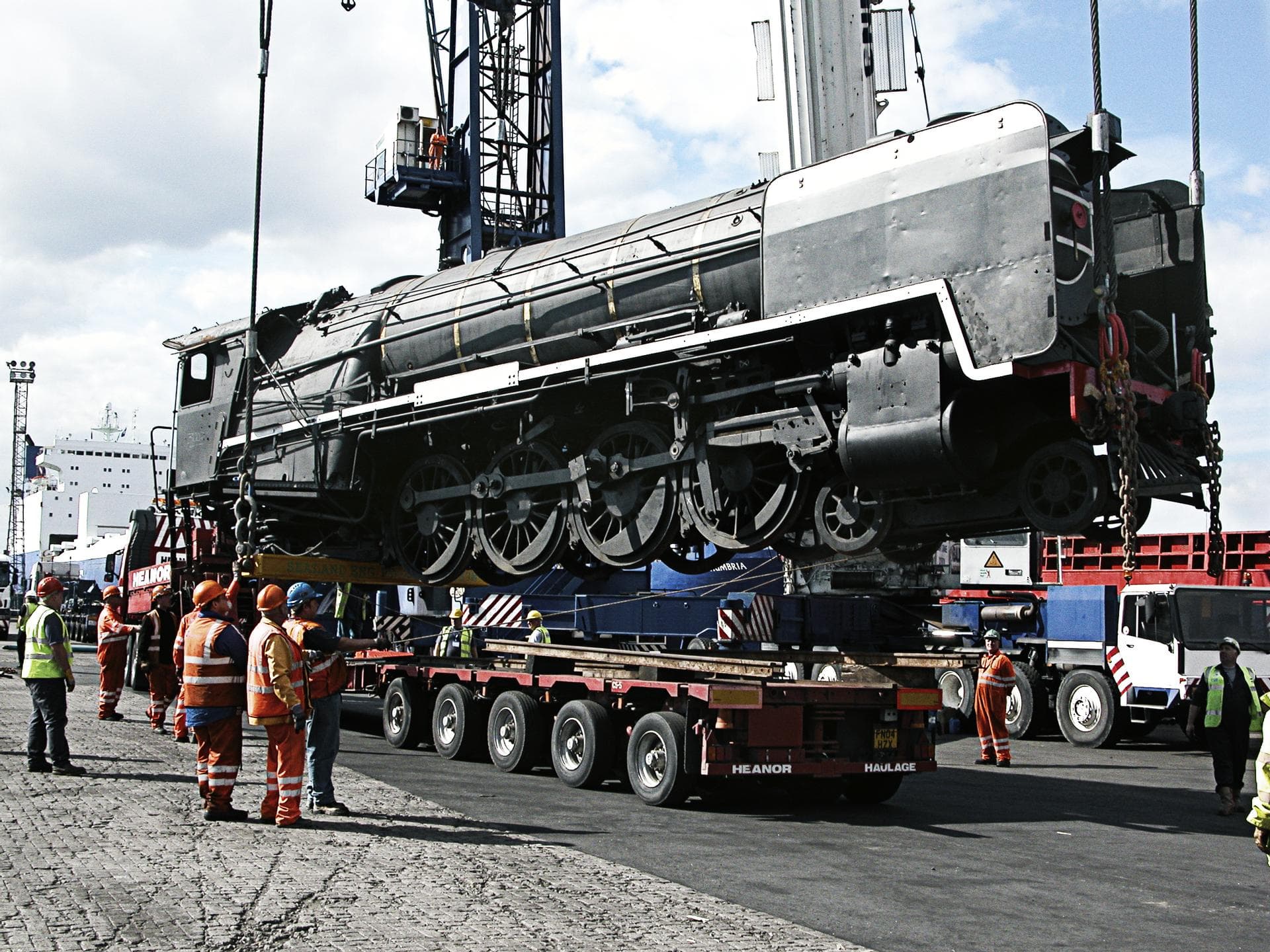 A train locomotive being loaded onto a truck by DFDS employees
