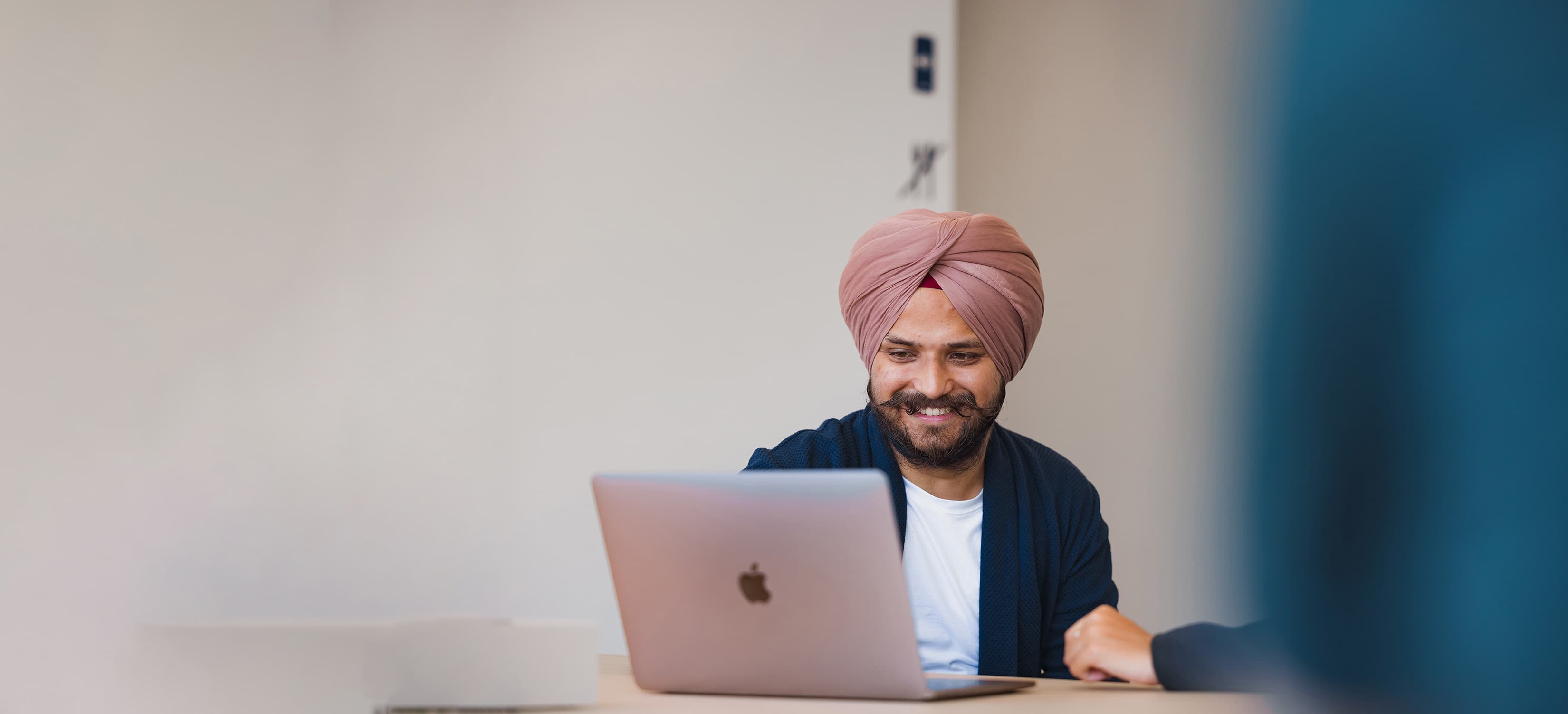 A DFDS employee, sitting at a desk, smiles while looking at a laptop