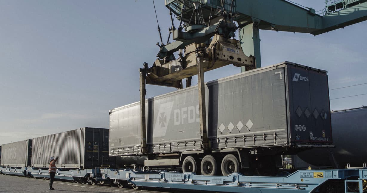 Gantry crane loading a DFDS trailer on rail.