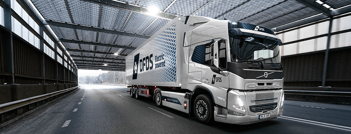 White electrical VOLVO truck, with white cold chain trailer, in DFDS livery, driving in a tunnel