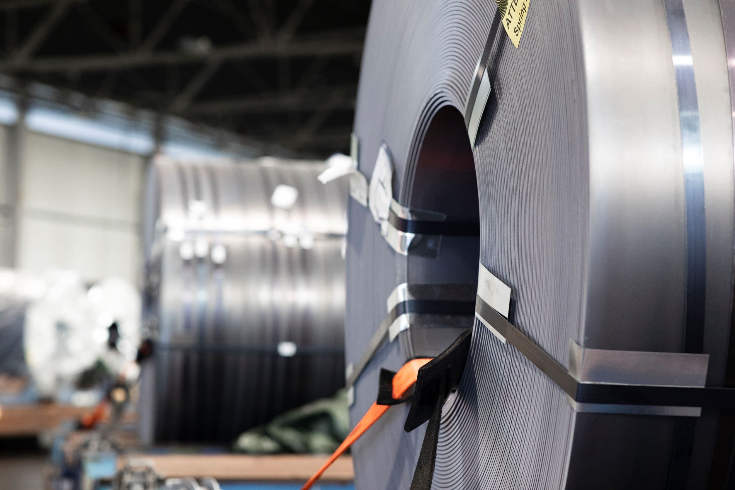 Metal coils strapped down to a trailer bed, being prepared for transport from a warehouse to it's destination.