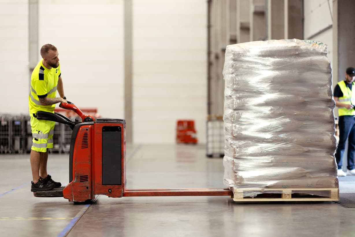 A DFDS worker moving a pick and pack pallet on the warehouse floor.